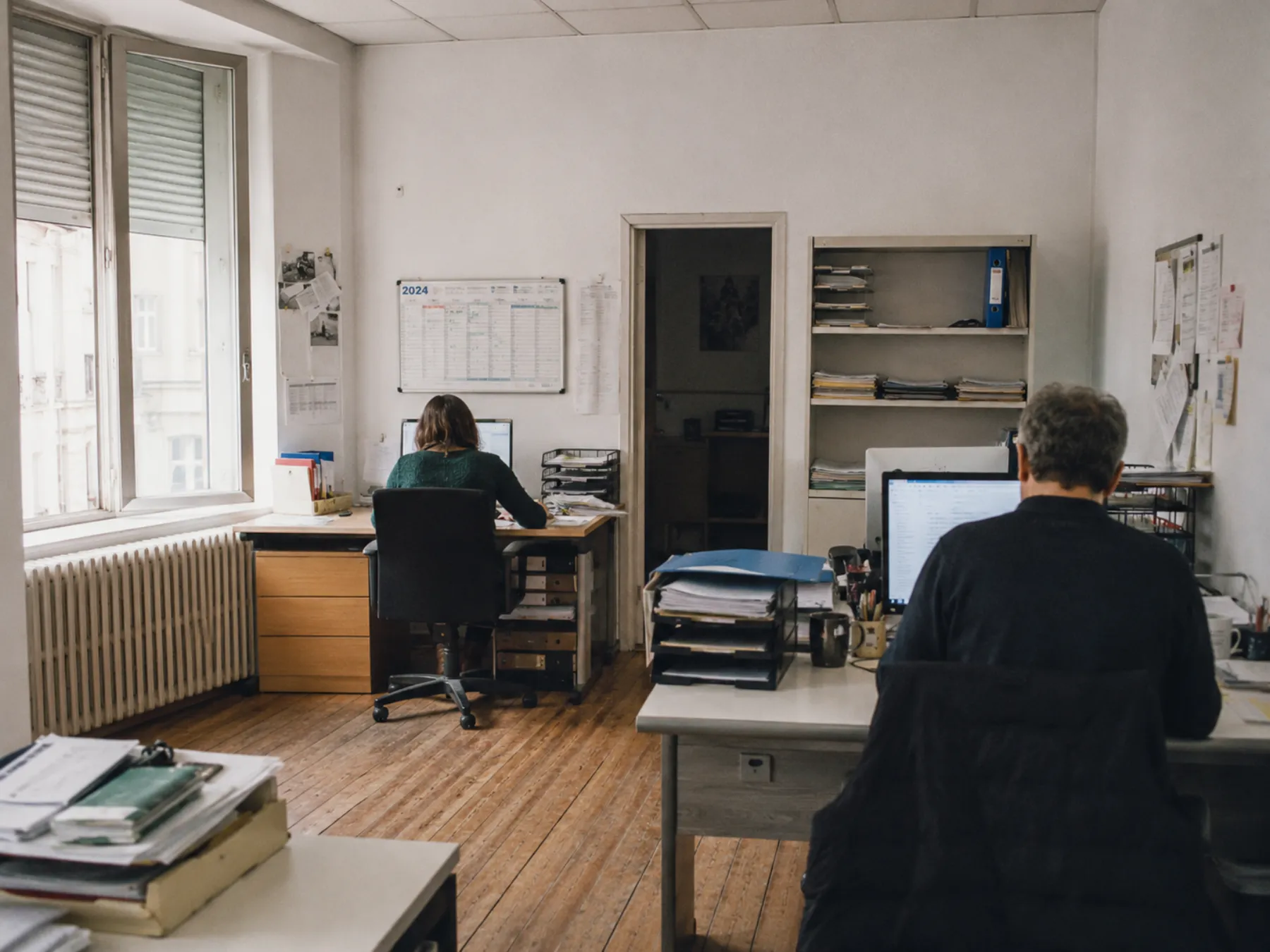 Open-space d'une entreprise : deux personnes travaillent sur leurs dossiers et écrans